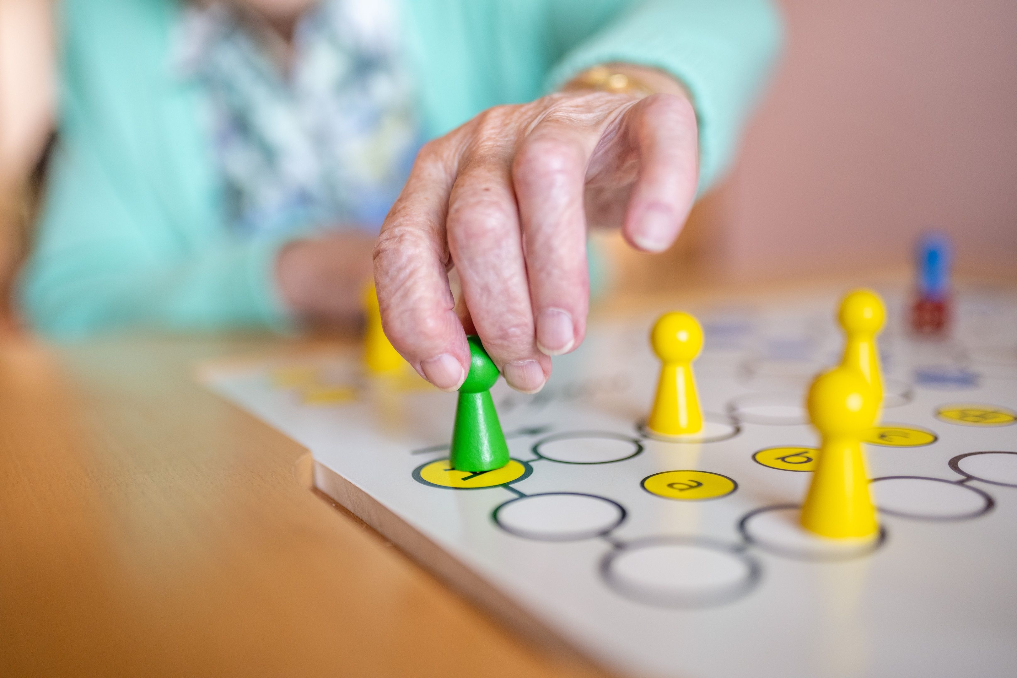 Seniorin setzt eine Spielfigur auf dem Spielbrett