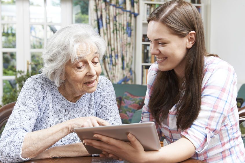Junge Frau zeigt einer Seniorin etwas auf dem Tablet